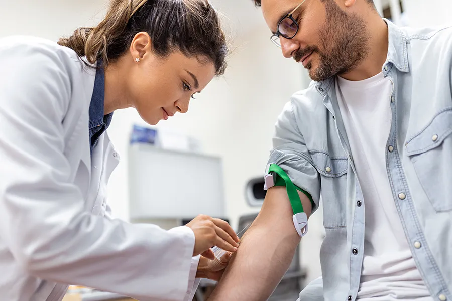 Nurse applying a tourniquet and getting a patient ready for a blood test during a routine exam